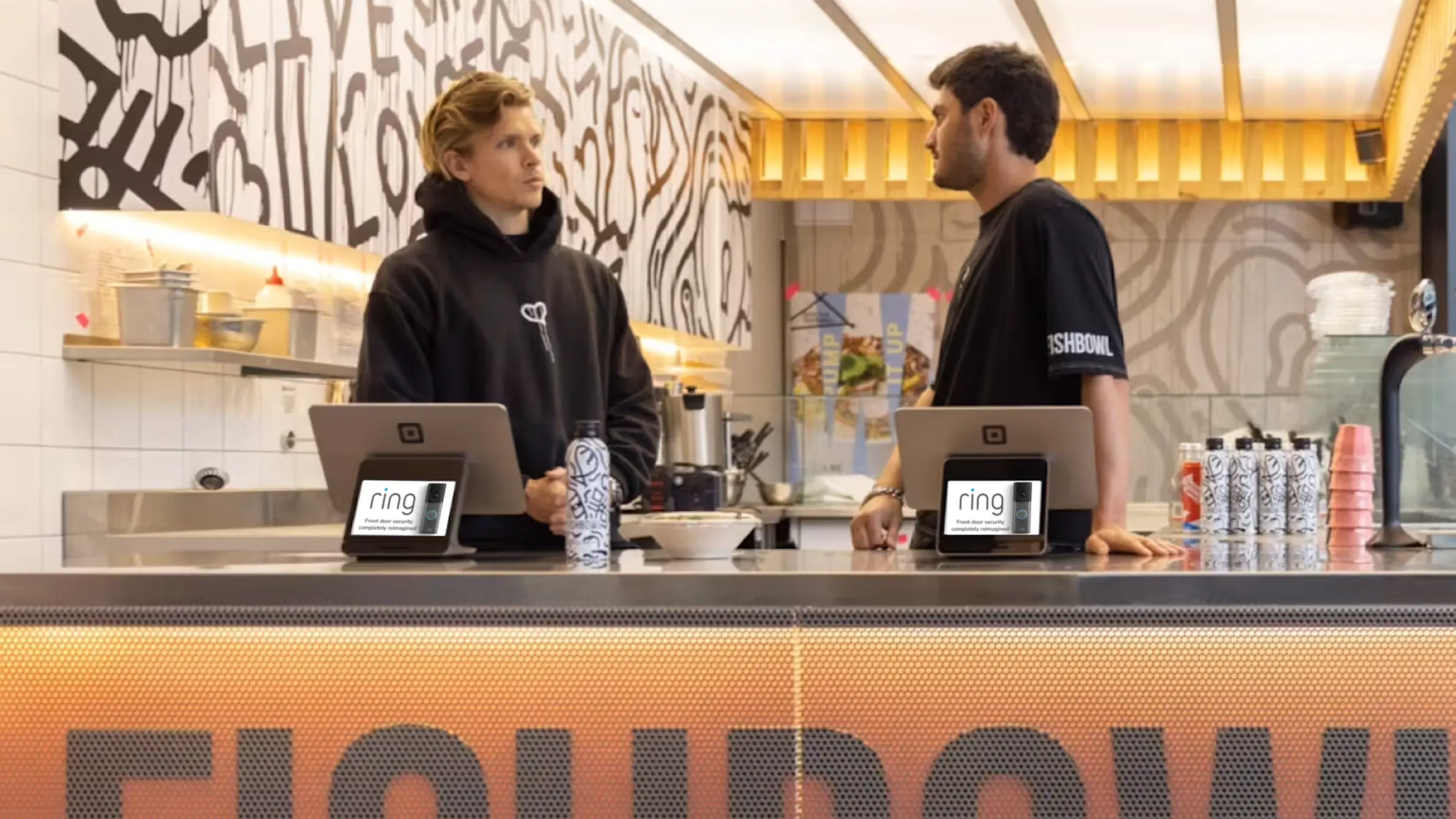 Payment terminals on a counter displaying a full-screen ad